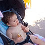 baby, bare_chest, child, chocolate, curly_hair, cute, food, messy, outdoor, playful, portrait, relaxing, seat, seatbelt, snack, stroller, summer, sunlight, toddler, yellow_chair