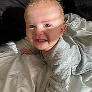 Cairo joined the competition — help win amazing prizes! baby, child, smiling, face, blond_hair, eyes, bed, blanket, clothing, gray_sweater, person, infant, happy, indoor, cute, light, shadow, skin, head, portrait