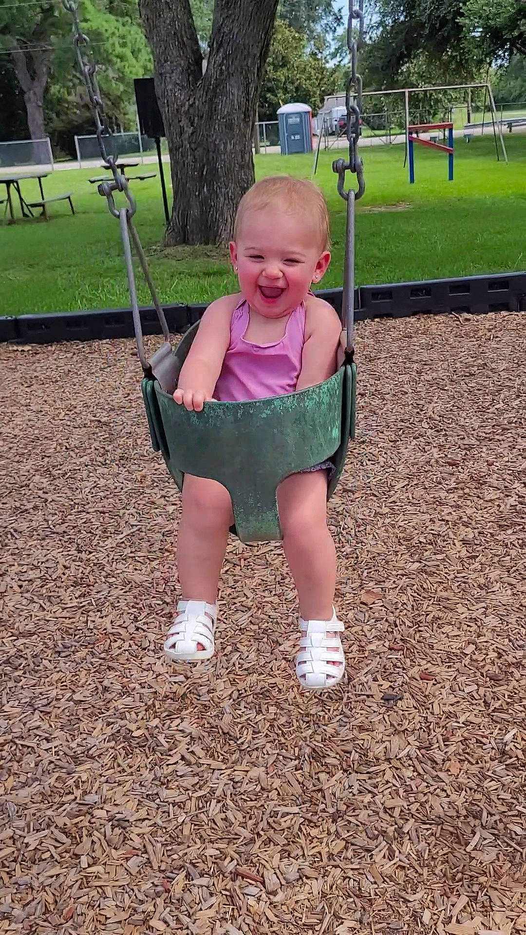 Delilah joined the competition — help win amazing prizes! baby_toddler_clothing, child, city, fun, grass, happy, joy, leisure, outdoor_play_equipment, people_in_nature, person, plant, playground, recreation, sitting, sleeve, smile, soil, swing, t_shirt