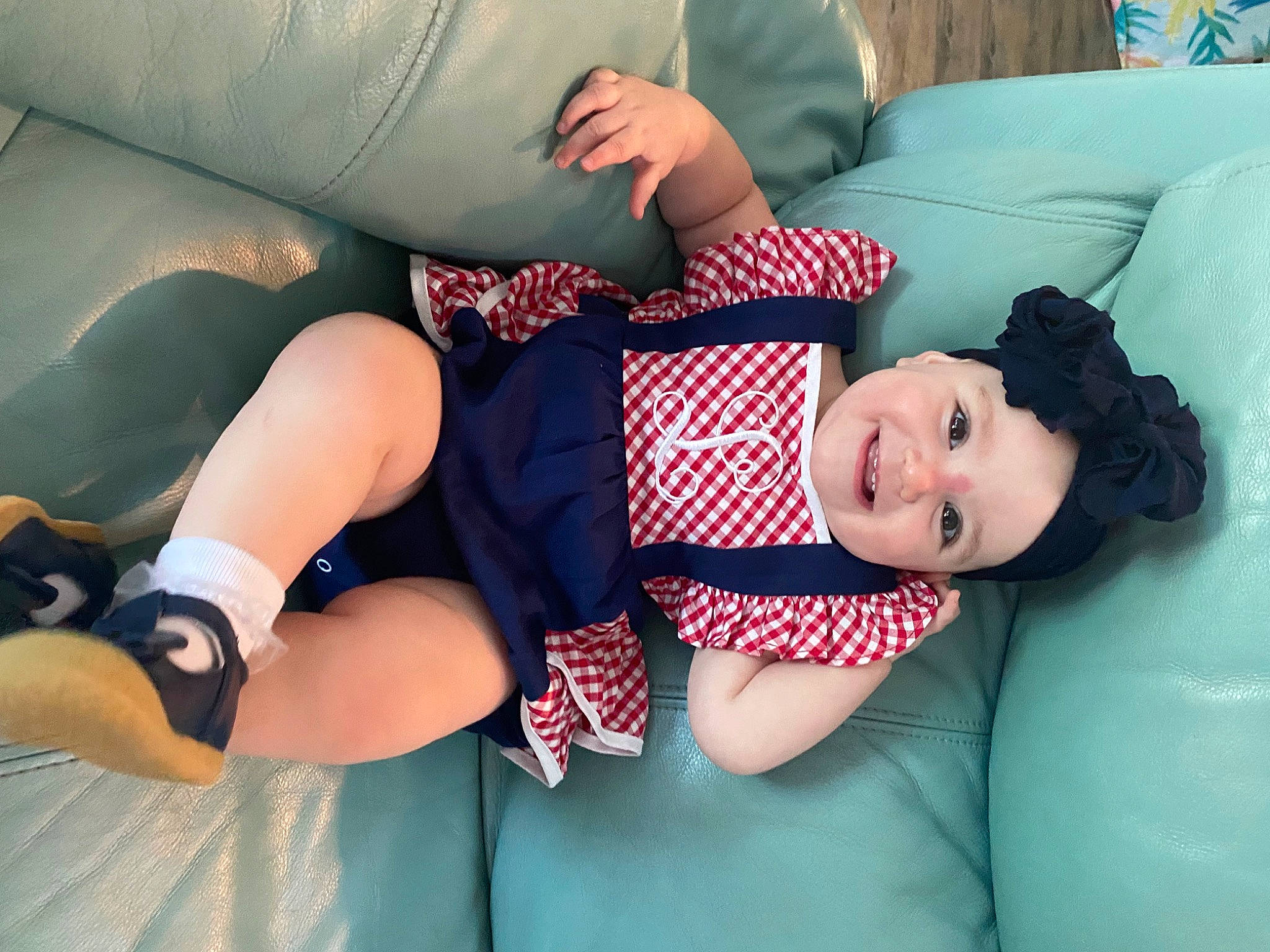 Lucy is registered to the contest to win money with this photo: arm, baby_toddler_clothing, child, comfort, couch, elbow, finger, headwear, human_leg, joint, joy, knee, lap, leg, mouth, person, shorts, sitting, smile, sock