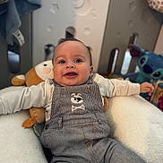 Tylio a rejoint le concours — aidez-le/la à gagner de superbes lots ! baby, background, child, clothing, cozy, cute, face, happy, indoor, infant, overalls, person, play_area, playpen, plush_toy, portrait, seated, smiling, soft_toy, toy