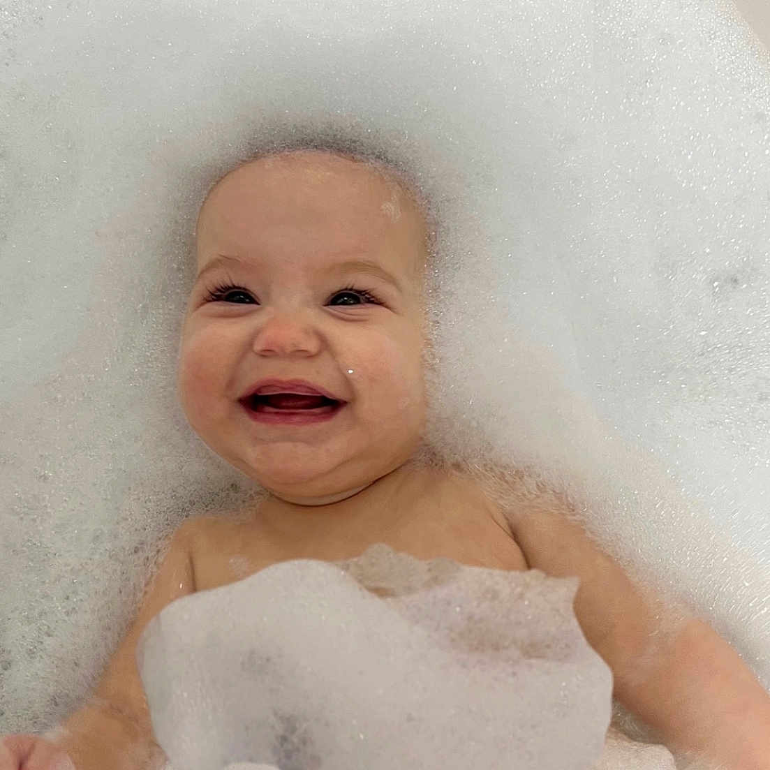 Thea is registered to the contest to win money with this photo: baby, babylaughing, bathing, bathtub, bubble, face, foam, happy, head, laughing, newborn, person, photography, portrait, smile, tub