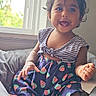 Kashif is registered to the contest to win money with this photo: toddler, child, smiling, window, dress, watermelon_pattern, striped_clothing, sitting, indoors, natural_light, happy, cute, soft_cushion, baby, person, portrait, short_hair, skin, hand, face