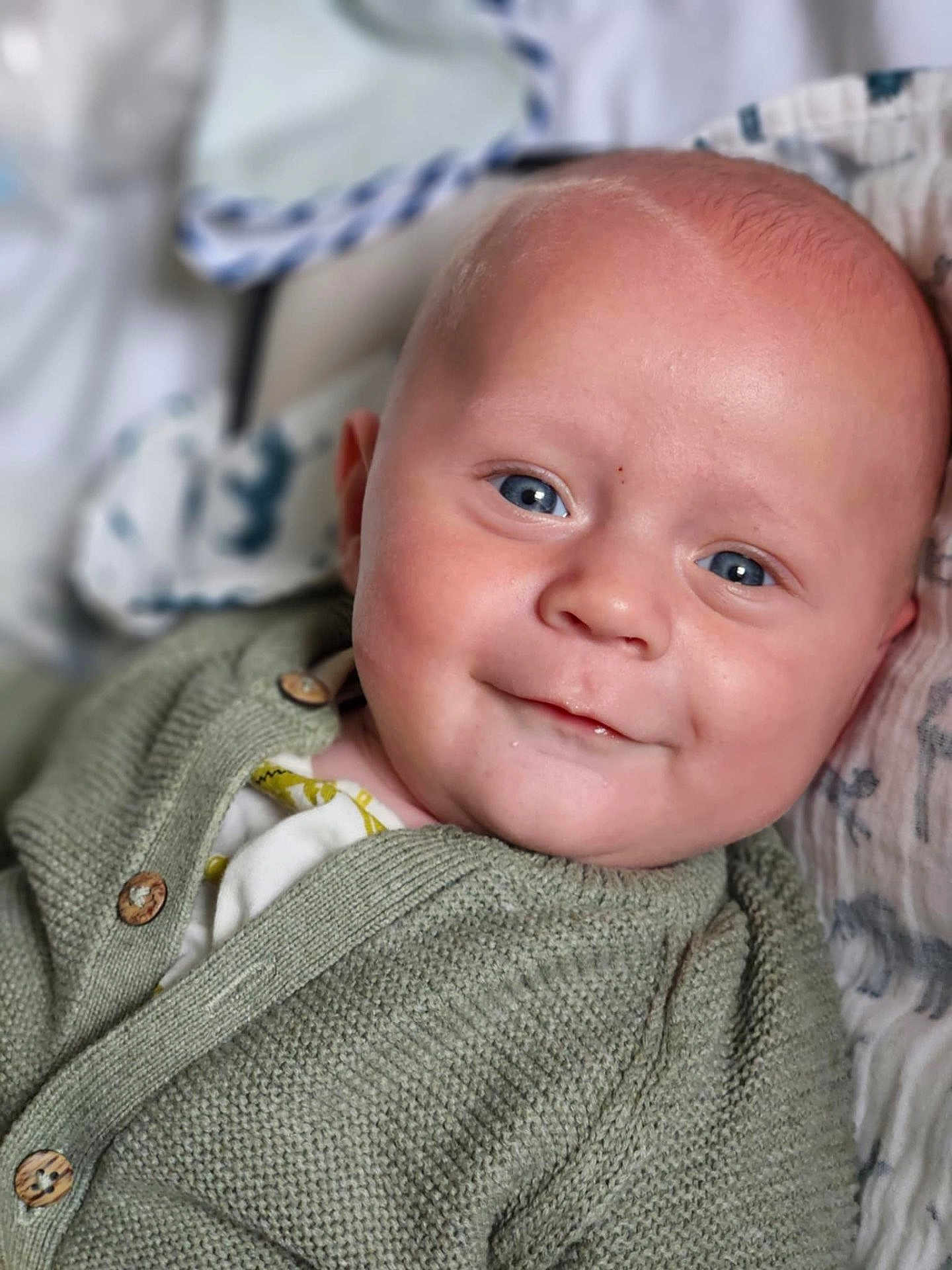 Léandre participe au concours pour gagner de l'argent avec cette photo : baby, smiling, blue_eyes, face, knit_cardigan, green_clothing, close_up, infant, child, soft_blanket, portrait, cute, happy, young_child, indoors, cozy, buttoned_clothing, head, skin, person