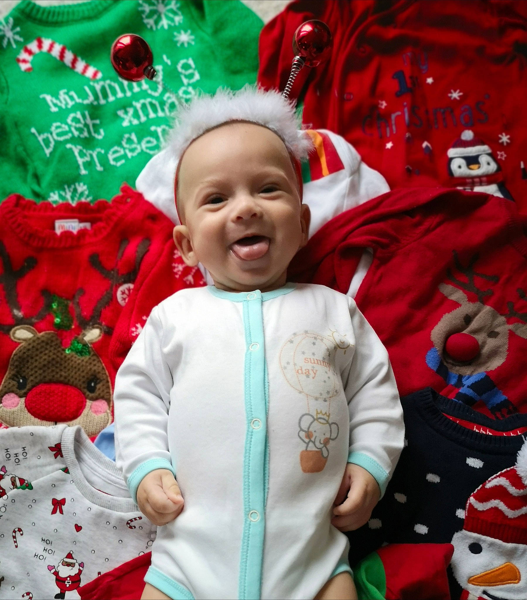 Sasha is registered to the contest to win money with this photo: baby, child, christmas, christmas_eve, event, fictional_character, happy, holiday, outerwear, person, red, sleeve, smile, toddler