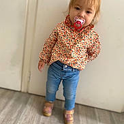 Elaïs a rejoint le concours — aidez-le/la à gagner de superbes lots ! blond_hair, casual_wear, child, curious, door, expression, floor, home, indoor, jeans, pacifier, patterned_clothing, person, portrait, shirt, shoes, standing, toddler, wooden_floor, young_child
