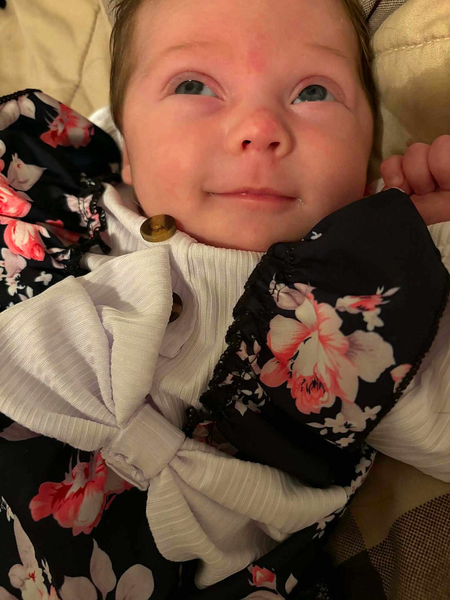 Emery joined the competition — help win amazing prizes! baby, infant, face, eyes, smile, clothing, floral_pattern, bow, fabric, button, hand, skin, portrait, cute, lying_down, indoors, soft_lighting, close_up, child, person