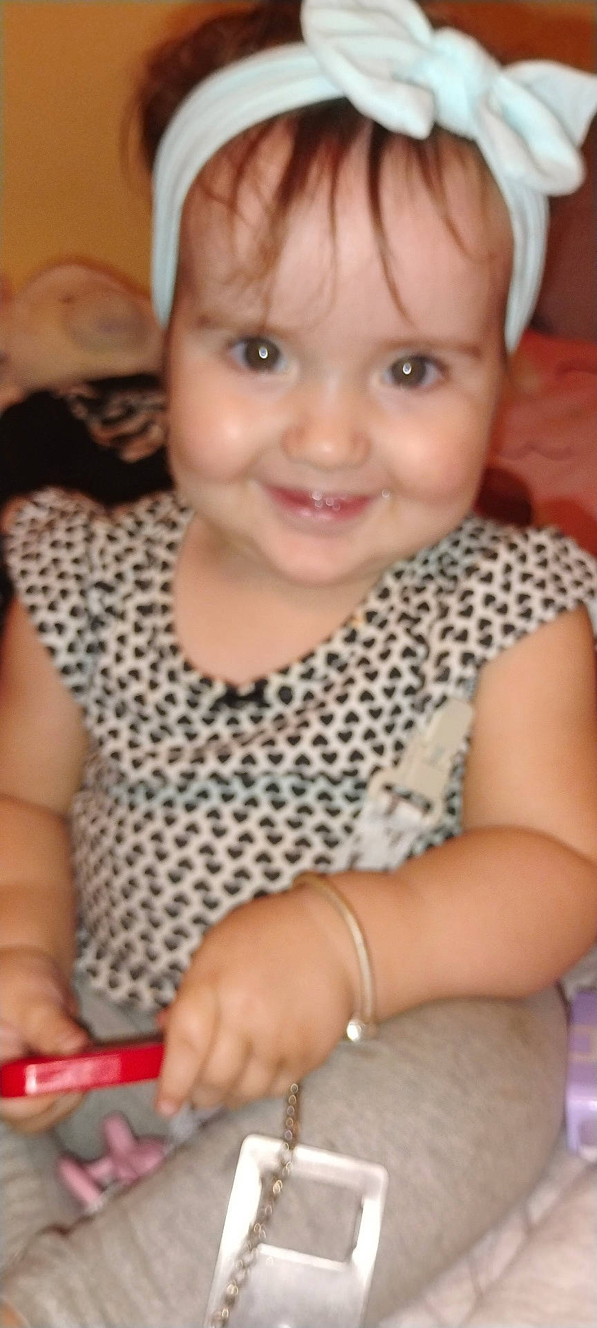 Helena joined the competition — help win amazing prizes! baby, bow, bracelet, child, closeup, clothing, cute, face, hand, happy, headband, indoor, patterned_shirt, person, playing, sitting, smile, toddler, toy, young_child