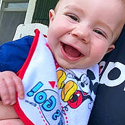 Loki is registered to the contest to win money with this photo: applique, baby, babylaughing, bib, bodypart, clothing, cushion, dress, face, happy, head, homedecor, laughing, mouth, person, photography, portrait, smile, t_shirt, teeth