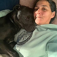 Max participe au concours pour gagner de l'argent avec cette photo : woman, dog, black_dog, lying_down, couch, hoodie, celestial_design, sun_and_moon, close_up, indoor, relaxing, pet, companion, affection, face, expression, casual_clothing, comfort, rest, bond