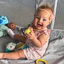 baby, child, smiling, playpen, toy, doll, yellow_ball, pink_outfit, headband, flower, mesh, fabric, blue_toy, red_toy, sitting, happy, cute, indoor, play, infant