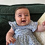Emy a rejoint le concours — aidez-le/la à gagner de superbes lots ! baby, child, smiling, blue_dress, floral_pattern, couch, pillow, indoor, happy, cute, face, human, person, sitting, infant, short_hair, cheeks, arm, hand, portrait