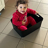 Eya a rejoint le concours — aidez-le/la à gagner de superbes lots ! toddler, child, smiling, curly_hair, red_clothing, minnie_mouse, storage_bin, indoor, tile_floor, happy, sitting, person, cute, playful, baby, home, plastic_container, floor, fun, young_child