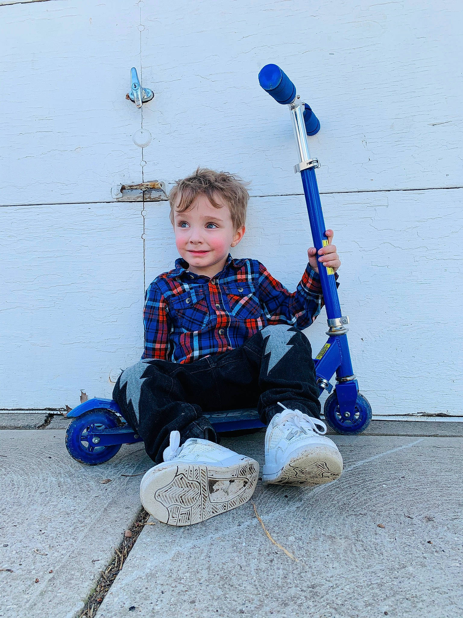 Lyam is registered to the contest to win money with this photo: baby_toddler_clothing, blue, child, city, concrete, denim, electric_blue, fun, joy, musical_instrument, person, play, plucked_string_instruments, recreation, shoe, sitting, smile, sneakers, t_shirt, tire