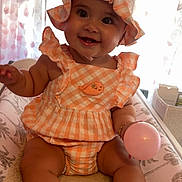 Jade a rejoint le concours — aidez-le/la à gagner de superbes lots ! baby, child, smiling, hat, gingham, orange, pink, ball, sitting, indoors, curtains, changing_pad, clothing, cute, happy, person, face, infant, plush, room