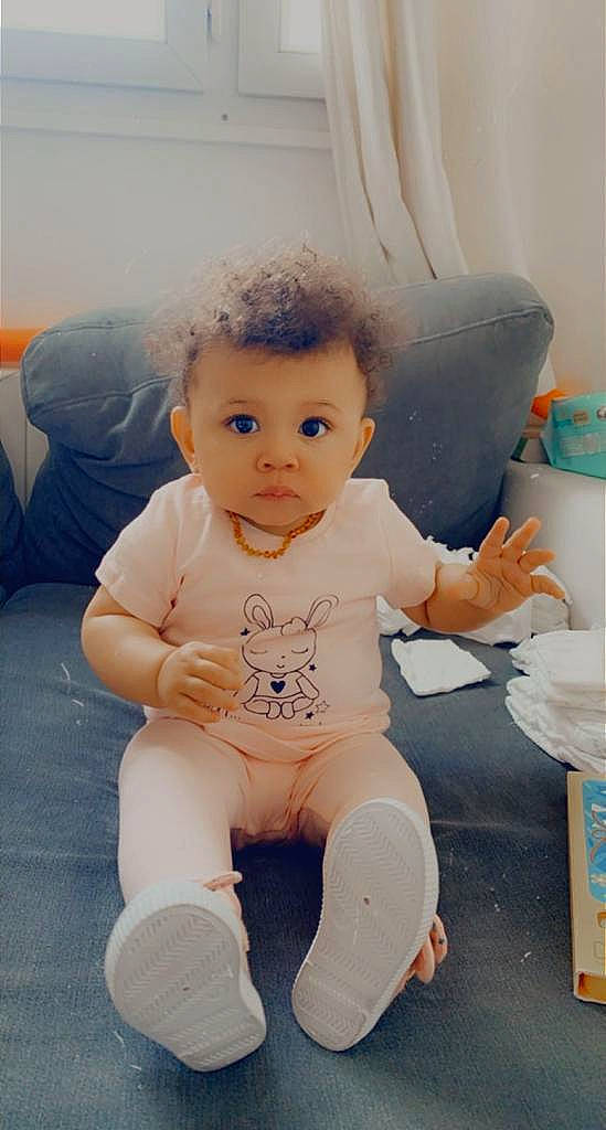 Lya a rejoint le concours — aidez-le/la à gagner de superbes lots ! baby, baby_toddler_clothing, barefoot, cheek, child, finger, floor, flooring, hairstyle, happy, joint, knee, lip, mouth, nose, person, pink, skin, stomach, thigh