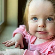 Delilah is registered to the contest to win money with this photo: toddler, child, face, blue_eyes, pink_clothing, window, natural_light, closeup, portrait, baby, skin, hand, hair, indoor, soft_light, expression, cute, young_child, person, looking
