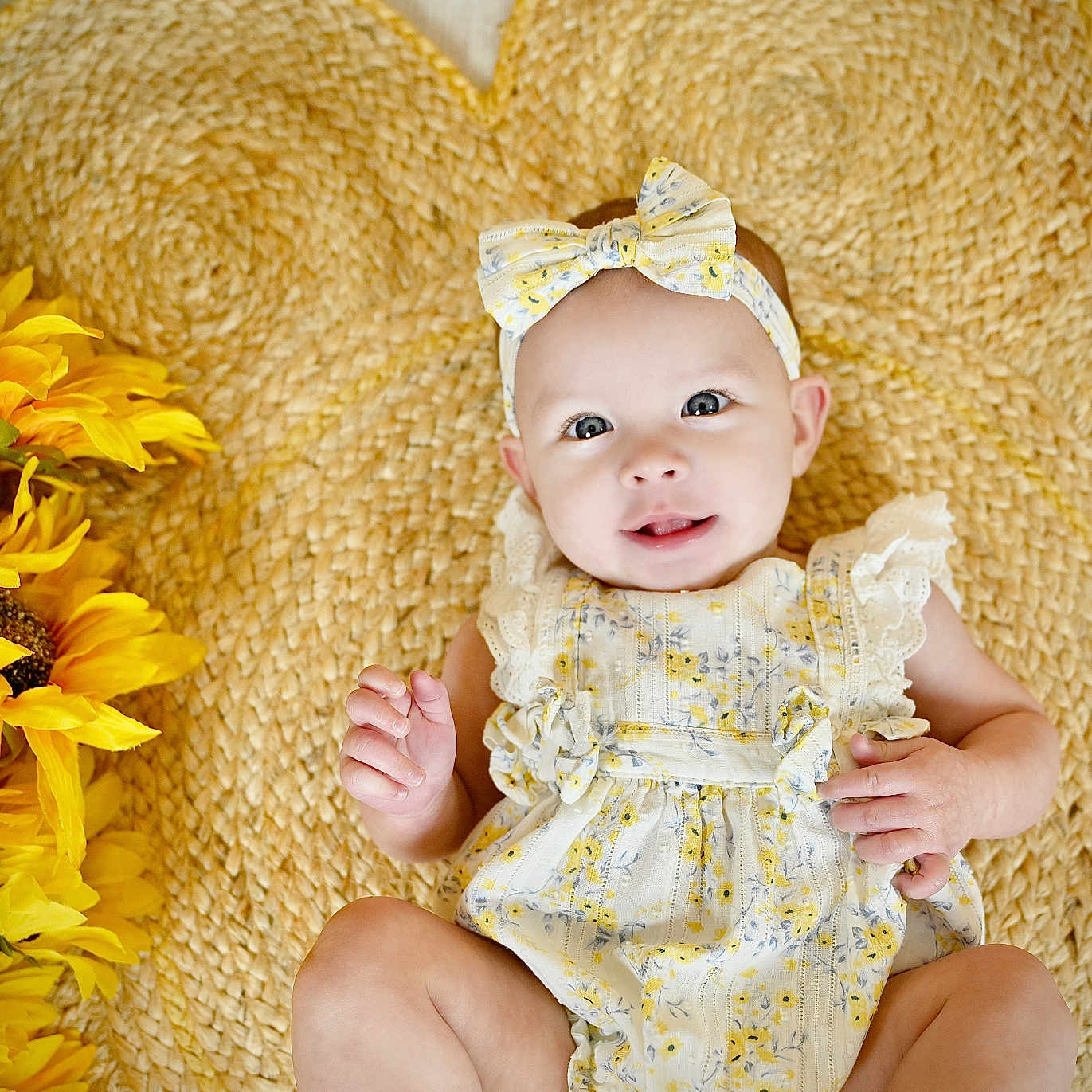 Mckinlyn joined the competition — help win amazing prizes! baby, child, clothing, cute, decor, eyes, face, flower, hand, happy, headband, indoor, infant, laying_down, portrait, skin, smile, sunflowers, woven_mat, yellow