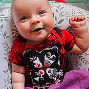 Charlotte joined the competition — help win amazing prizes! baby, infant, smiling, red_tshirt, kiss_band, purple_blanket, pillow, floral_pattern, cute, happy, indoors, portrait, child, face, hand, skin, clothing, lying_down, cozy, expression