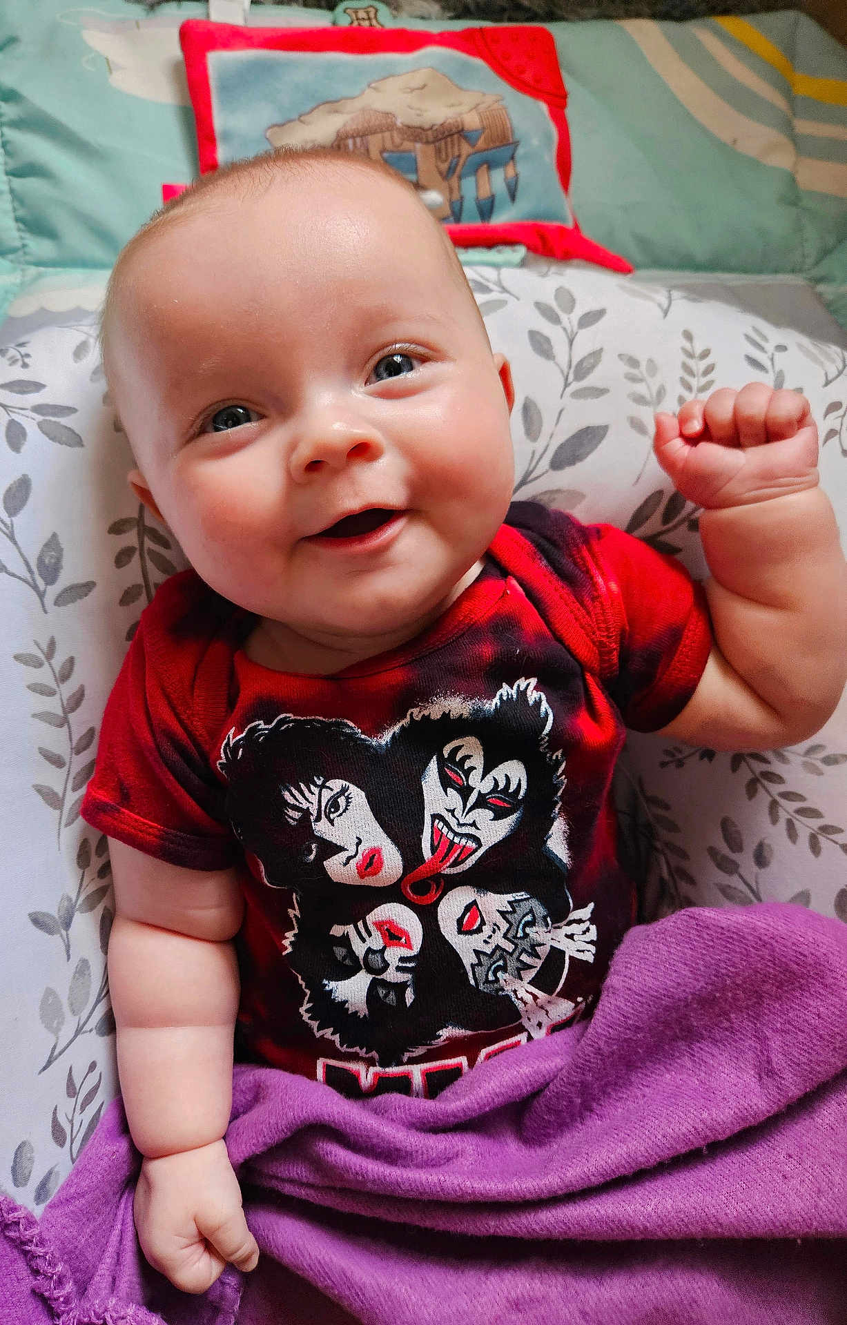 Charlotte joined the competition — help win amazing prizes! baby, infant, smiling, red_tshirt, kiss_band, purple_blanket, pillow, floral_pattern, cute, happy, indoors, portrait, child, face, hand, skin, clothing, lying_down, cozy, expression