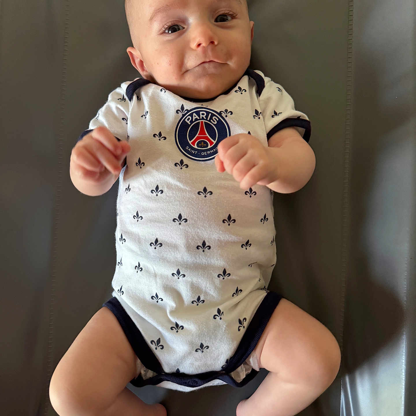Gabriel a rejoint le concours — aidez-le/la à gagner de superbes lots ! baby, child, clothing, cute, expression, face, feet, gray_background, hands, indoor, infant, legs, lying_down, newborn, onesie, paris_saint_germain, person, portrait, skin, smiling