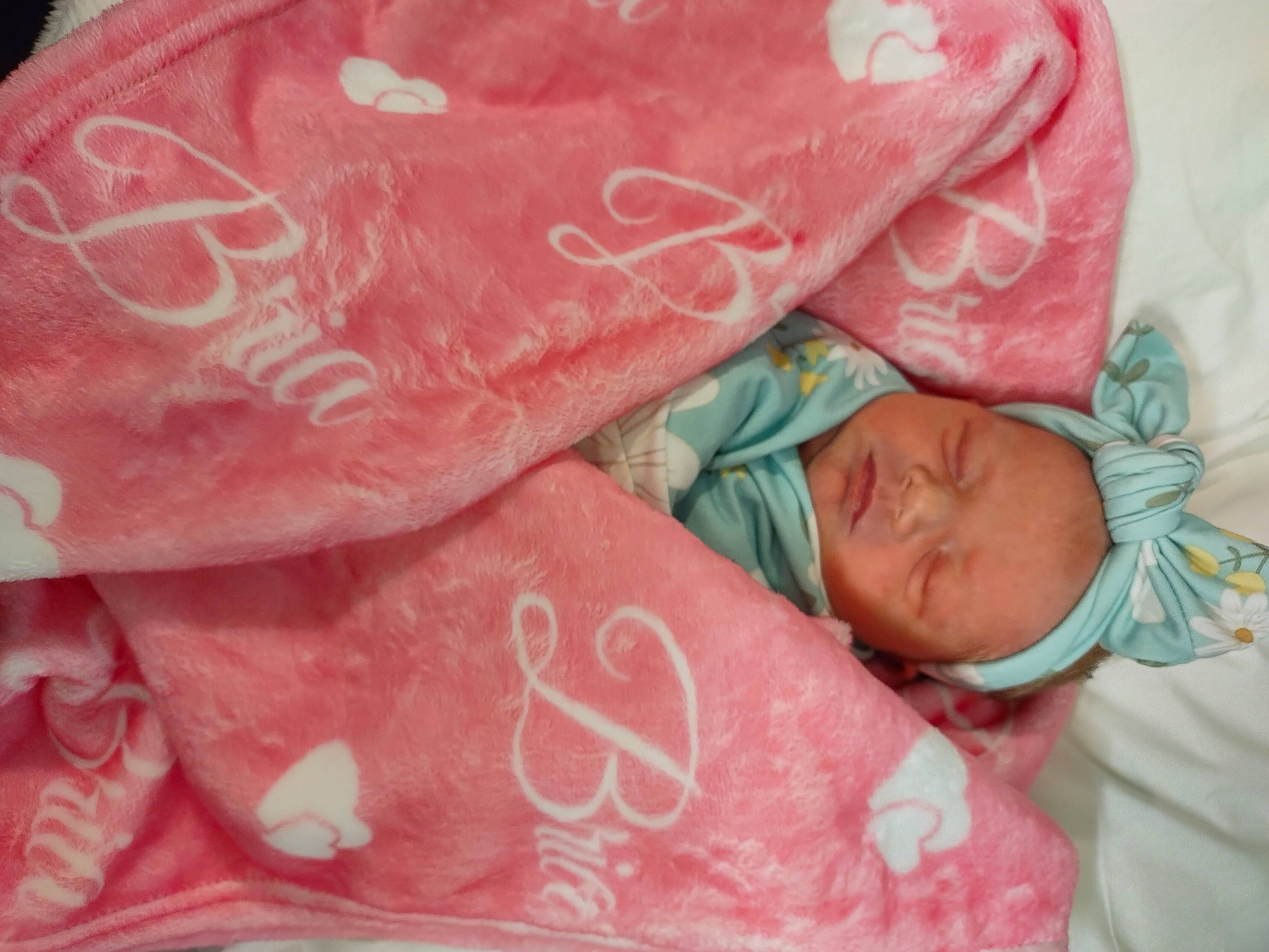 Bria is registered to the contest to win money with this photo: baby, baby_sleeping, baby_toddler_clothing, bedding, carmine, child, comfort, fashion_accessory, flesh, font, linens, lip, magenta, pattern, peach, person, pink, skin, sleeve, textile