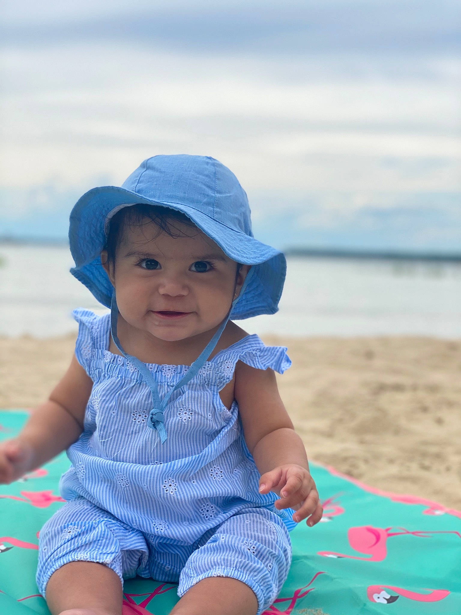 Alia is registered to the contest to win money with this photo: baby, beach, blue, child, fun, hat, headgear, headwear, ocean, person, pink, play, sand, sea, sitting, skin, smile, summer, sun_hat, textile
