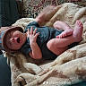 baby, blanket, hat, yawning, feet, hand, couch, fabric, indoor, infant, clothing, person, sleepy, cute, soft, patterned_rug, relaxing, small, comfortable, toddler