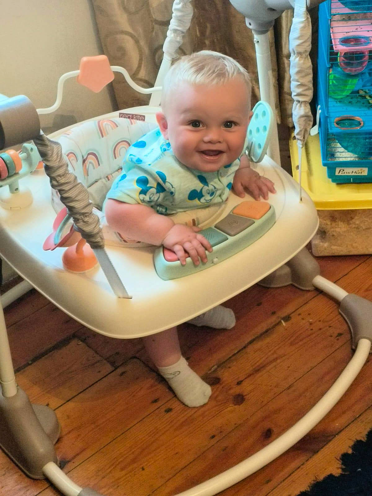 Parker joined the competition — help win amazing prizes! baby, baby_jumper, blond_hair, child, clothing, cute, face, floor, furniture, happy, indoor, infant, person, pet_cage, playtime, room, smiling, sock, toy, wooden_floor