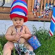 Mateo is registered to the contest to win money with this photo: baby, beads, blue, bucket, celebration, child, concrete, decorations, diaper, door, festive, grass, hat, outdoor, patriotic, porch, red, star_shaped_glasses, summer, white
