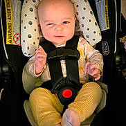 Amelia joined the competition — help win amazing prizes! baby, car_seat, infant, winking, yellow_pants, patterned_shirt, socks, straps, safety_harness, cute, indoor, child, person, seat, head_support, playful, expression, smile, closeup, adorable