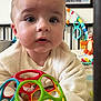 baby, infant, toy, colorful_toy, plastic_ball, plush_toy, bed, blanket, face, eyes, clothing, indoor, poster, titanic, curious, child, person, crawling, home, cute