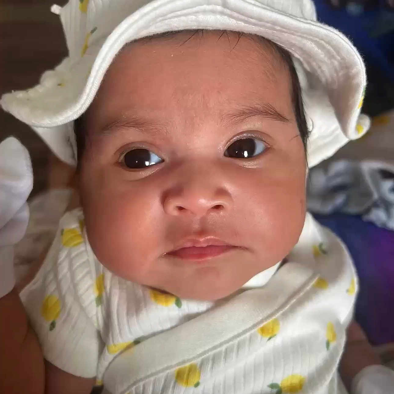 Raqueesha is registered to the contest to win money with this photo: apparel, baby, child, closeup, clothing, cute, expression, eyes, face, hat, headwear, indoors, infant, newborn, pattern, portrait, skin, soft, white, yellow