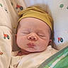 newborn, baby, sleeping, infant, portrait, face, hat, yellow_hat, swaddled, blanket, crib, bedding, nursery, indoors, peaceful, resting, closed_eyes, farm_animals, tractor_pattern, soft_lighting
