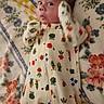 newborn, baby, infant, child, portrait, lying_down, floral_blanket, onesie, baby_clothing, patterned_clothing, vegetables, bugs, wide_eyed, eyes, face, head, arms, indoor, bed, colorful