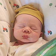 Christian is registered to the contest to win money with this photo: newborn, baby, sleeping, infant, portrait, close_up, face, yellow_hat, beanie, blanket, green_blanket, swaddled, bedding, crib, nursery, tractor_pattern, textile, peaceful, indoors, photograph