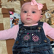 Iris is registered to the contest to win money with this photo: baby, infant, pink_bow, denim_overalls, embroidered_flowers, patchwork_quilt, animal_print, cat_print, dog_print, lying_down, cute, child, face, headband, clothing, portrait, indoor, chubby_cheeks, curious_expression, soft_lighting