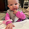 baby, infant, child, high_chair, pink_clothing, bib, hand, face, smile, indoor, kitchen, toy, beads, curious, cute, person, young_child, table, expression, seat