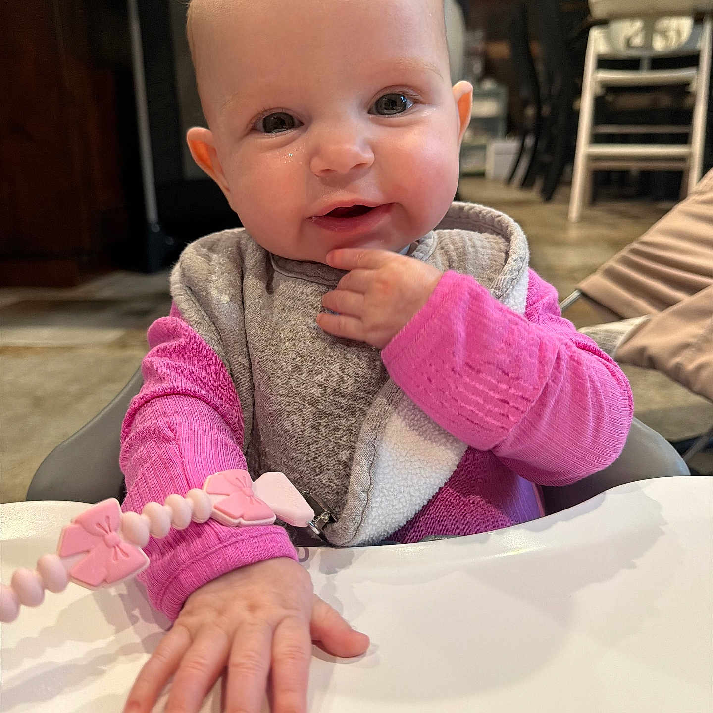 Sage joined the competition — help win amazing prizes! baby, infant, child, high_chair, pink_clothing, bib, hand, face, smile, indoor, kitchen, toy, beads, curious, cute, person, young_child, table, expression, seat
