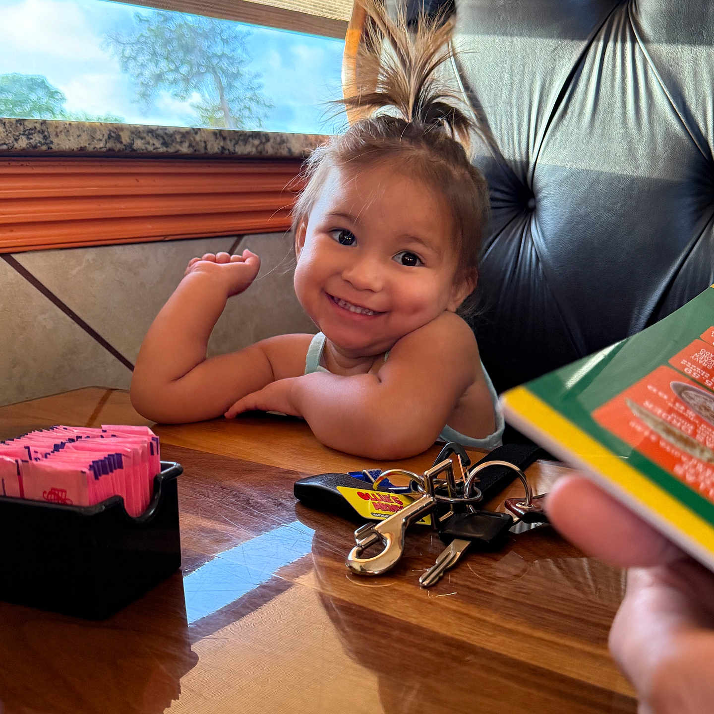 Elizabeth joined the competition — help win amazing prizes! arm, casual, chair, child, dimples, face, happy, indoor, keys, menu, person, pony_tail, restaurant, smile, sunlight, sweetener_packets, table, toddler, window, wooden_table