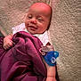 Kaia is registered to the contest to win money with this photo: baby, smiling, blanket, pacifier, infant, sleepy, cushion, cozy, soft, white_clothing, hand, face, cute, resting, indoors, child, newborn, comfort, lying_down, relaxed