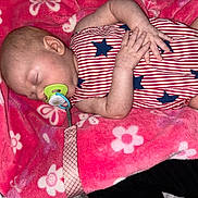 Kaia is registered to the contest to win money with this photo: baby, sleeping, pacifier, blanket, red, blue, striped_clothing, stars, infant, hand, face, head, skin, cute, rest, cozy, floral_pattern, soft, comfort, nap