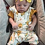 Kaia is registered to the contest to win money with this photo: baby, infant, child, headband, yellow_bow, floral_overalls, baby_seat, cushion, soft_fabric, wooden_floor, indoors, clothing, person, portrait, cute, comfort, relaxed, small_hands, small_feet, young