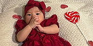 Nahara is registered to the contest to win money with this photo: adorable, baby, blanket, child, cute, decorations, face, festive, hands, headband, heart, holiday, indoors, infant, lollipop, lying_down, portrait, red_dress, soft_texture, valentine