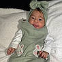 baby, child, infant, cute, bunny_patches, green_outfit, headband, bow, tongue_out, white_blanket, soft_texture, sleepwear, portrait, smiling, hand, face, eyes, indoor, cozy, playful