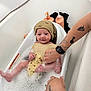 baby, bathtub, bubbles, child, foam, hand, hat, infant, person, skin, tattoo, water, wash, yellow_cloth, bath, bathroom, cute, smile, sitting, adult