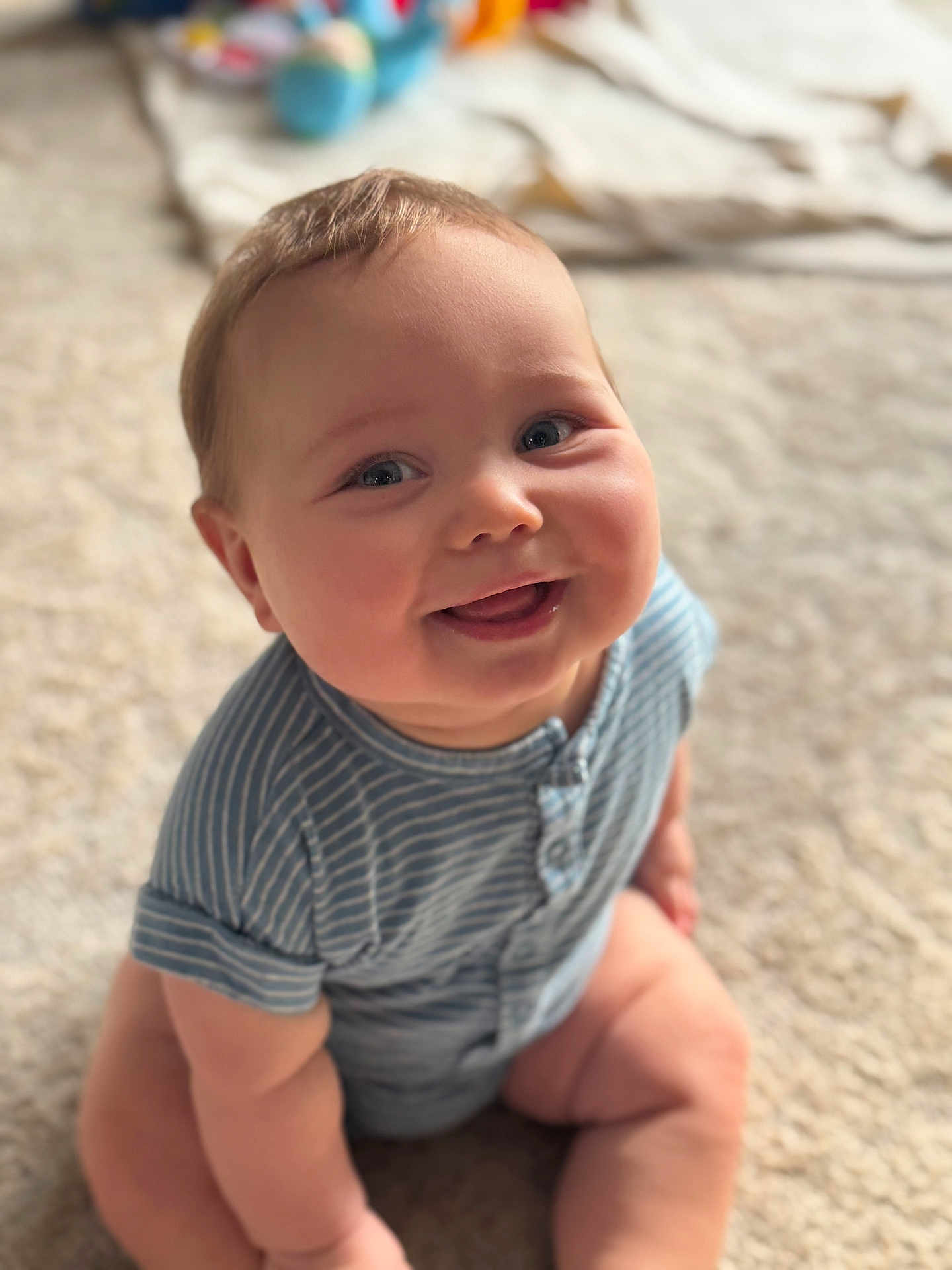 Lucas joined the competition — help win amazing prizes! baby, child, smiling, sitting, blue_clothing, striped, onesie, carpet, indoors, cute, chubby, happy, face, head, infant, person, portrait, skin, soft_light, young