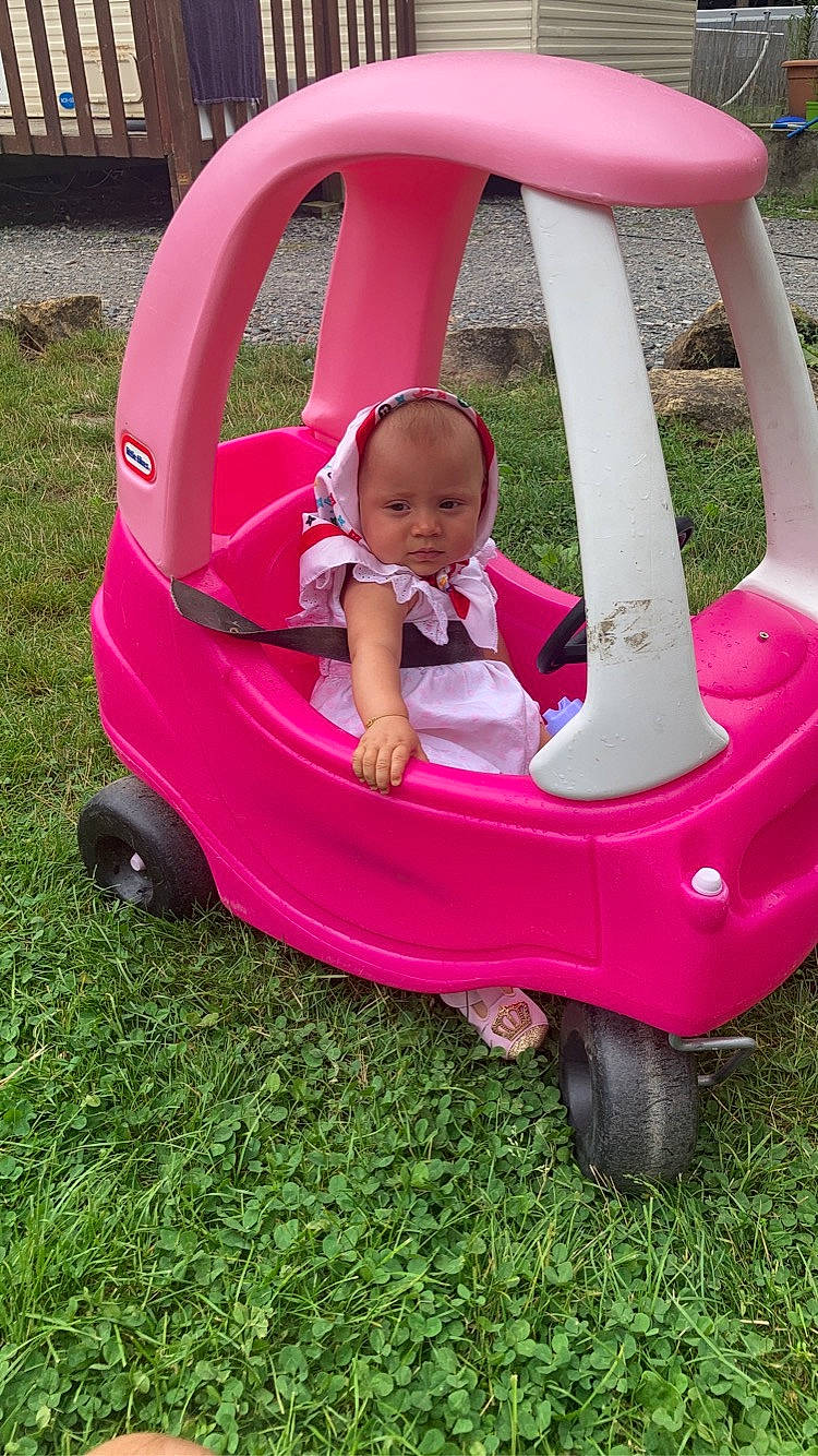 Cassy a rejoint le concours — aidez-le/la à gagner de superbes lots ! baby_toddler_clothing, comfort, face, grass, green, leisure, magenta, motor_vehicle, person, photograph, pink, plant, purple, recreation, red, riding_toy, tire, toddler, vehicle, wheel