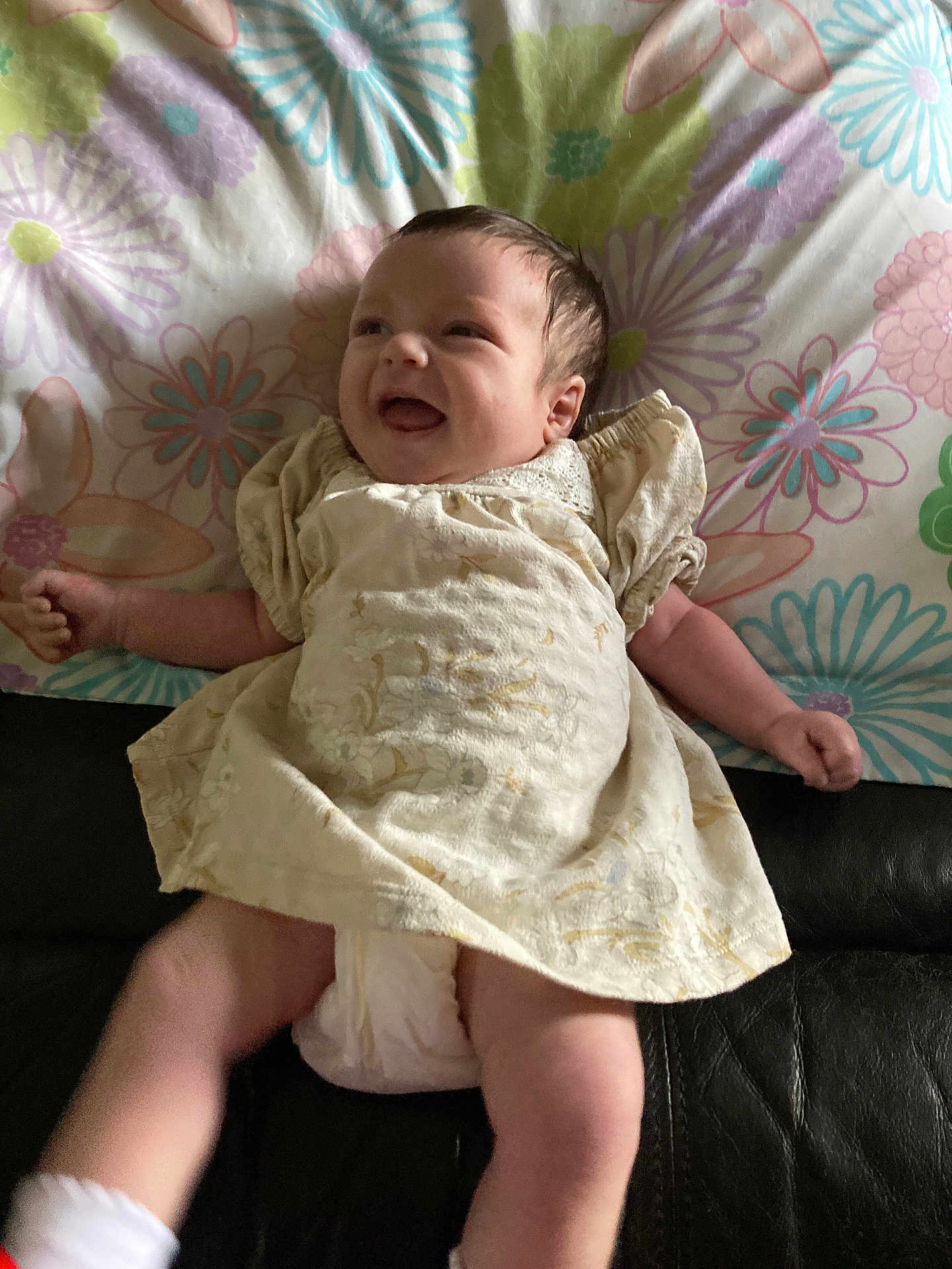 Luna is registered to the contest to win money with this photo: baby, newborn, infant, smiling, dress, diaper, blanket, floral_pattern, pillow, couch, indoors, portrait, legs, arms, socks, happy, cute, head, face, soft_lighting
