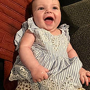 Luna is registered to the contest to win money with this photo: baby, child, smiling, laughing, dress, striped, lace, leopard_print, pants, sitting, couch, cushion, indoor, happy, person, infant, cute, portrait, face, hand